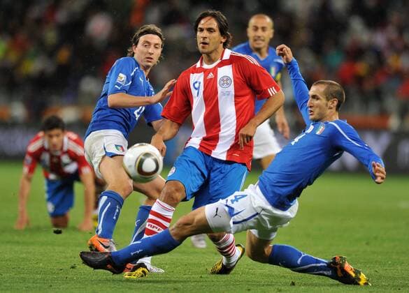 Giorgio Chiellini (R) and Riccardo Montolivo (L) of Italy fight for the ball with Roque Santa Cruz of Paraguay (C) during their Group F first round match at 2010 FIFA World Cup at Green Point stadium in Cape Town 