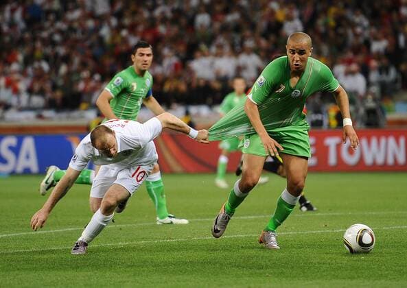 Football - 2010 FIFA World Cup - England vs. Algeria England s Wayne Rooney (L) pulls the shirt of Madjid Bougherra of Algeria at Green Point Stadium, Cape Town 