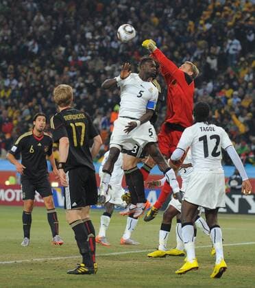 Goalkeeper Manuel Neuer of Germany punches clear under pressure from John Mensah (5) of Ghana - Group D, Ghana vs Germany - EDITORIAL USE ONLY. No use with unauthorised audio, video, data, fixture lists, club league logos or live services. Online in-match use limited to 120 images, no video emulation. No use in betting, games or single club league player publications.