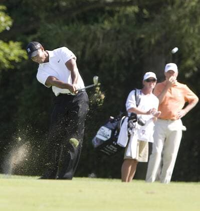 Tiger Woods chips up to hole 14 from the fairway as playing partner Dave Love III and his caddie watch during first round play of the AT&T National at Aronimink Golf Club in Newtown Square, Pennsylvania on July 1, 2010. Woods finished the day with a 3 over par 73.  PHI2010070103