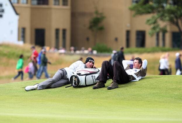 Golf - The British Open - St Andrews Due to high winds causing the balls to oscillate play has been suspended during the second day of the open. Picture is Bubba Watson (USA, L) and his caddie sitting on the Seventeenth green. 