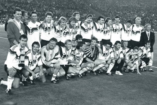 WM 1990, Finale in Rom, BR Deutschland ist Weltmeister - hi.v.li.: Co Trainer Holger Osieck, Bundestrainer Franz Beckenbauer, Klaus Augenthaler, Stefan Reuter, Jürgen Klinsmann, Frank Mill, Guido Buchwald, Paul Steiner, Thomas Bethold, Andreas Köpke, Jürgen Kohler, Andreas Möller, Hans Pflügler und Co Trainer Berti Vogts; vorn: Pierre Littbarski, Olaf Thon, Torwarttrainer Sepp Maier, Andreas Brehme, Lothar Matthäus mit dem Weltpokal, Karl Heinz Riedle (verdeckt), Torwart Bodo Illgner, Uwe Bein, Günther Hermann, Rudi Völler, Thomas Häßler und Raimond Aumann o0 Sieg Jubel Freude Pokal Trophäe Objekte Totale Siegerfoto Mannschaftsfoto Kader Hansi Karlheinz