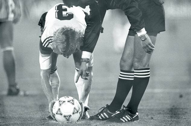 WM 1990, Hochspannung beim Finale in Rom - Andreas Brehme (BR Deutschland) legt sich besonders sorgfältig den Ball für den entscheidenden Elfmeter zurecht, denn Schiedsrichter Edgardo Codesal Mendez (Mexiko) will es ganz genau wissen o0 Gestik Körperteile Arm Hand Spannung BRD