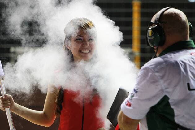 Grid girls are as much a part of international motorsports as high-octane fuel, ear plugs, and fiery crashes. Before each race, grid girls take up positions behind the starting line, holding up the national flag of the team and the vehicle s number, or holding umbrellas above the leather-clad riders to keep the sun off of them on the scorching asphalt. They also, it seems, spend a good deal of time just hanging out and looking absurdly hot. Long may they wave. Pictured: Sept. 26, 2010 - Singapore - COOLING OFF - A Lotus mechanic blows air chilled with dry ice onto a grid girl before the Formula One World Championship 2010 Singapore Grand Prix at the Marina Bay Street Circuit. Meanwhile back on the main track Alonso wins the race. --- - ZUMAs04 o0 Gridgirl Rauch Rauchwolke Rauchschwaden Qualm Qualmwolke Fotoshooting