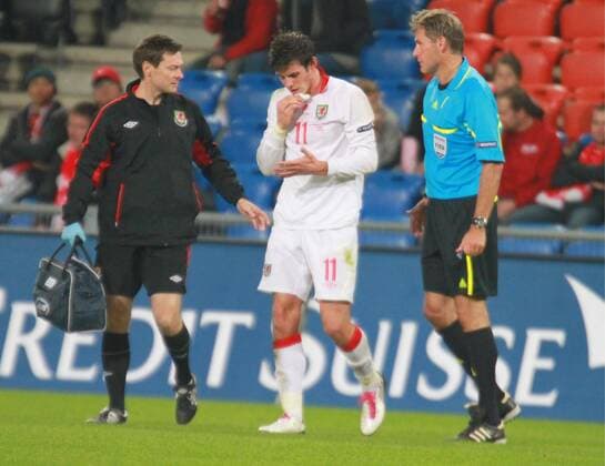 12.10.2010, Basel - EURO Quali 2010 - Schweiz vs Wales --- Gareth Bale (Wales) verletzt, rechts Schiedsrichter Alain Hamer (Luxemburg) 