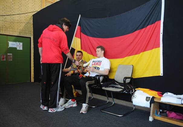 Bundestrainer Joachim LÖW (stehend) spricht mit Lukas PODOLSKI (li.) und Manuel NEUER Spieler in Fan-Outfit --- Werbedreh für den DFB-Generalsponsor Mercedes-Benz mit der deutschen Männernationalmannschaft in Kaiserau o0 Objekte Fahne, Nationalfahne Deutschlandfahne