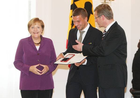 Dienstag 05.10.2010, Berlin, Verleihung des Silbernen Lorbeerblattes an die Deutsche Fussball-Nationalmannschaft durch Bundespräsident Christian Wulff im Schloss Bellevue. Bundeskanzlerin Dr. Angela Merkel (GER) , Lukas Podolski (GER) und Bundespräsident Christian Wulff DeFodi018