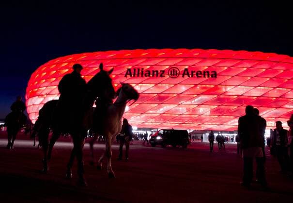 Berittene Polizei reitet auf Pferden vor der rot beleuchtetes Stadion Allianz Arena vorbei, Heimspielstätte des FC Bayern München o0 Tier Pferd Sicherheit Polizei Polizist Sponsor, Werbepartner, Werbung, Wirtschaft