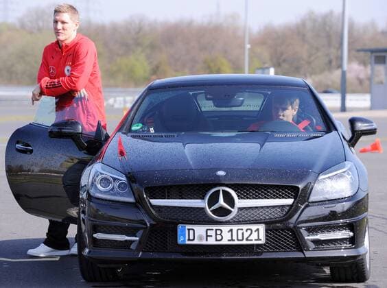 Der Nationalspieler Bastian SCHWEINSTEIGER (l. DFB) steht an einem Mercedes-Benz SLK 350 BlueEFFICIENCY. Rechts sitzt Holger BADSTUBER (DFB) am Steuer. Fussball: Driving-Experience Fahrsicherheitstraining der deutschen Fussball Nationalmannschaft der Männer auf der Strecke des ADAC-Fahrsicherheitszentrum in Grevenbroich, 28.03.2011. Poolfoto.