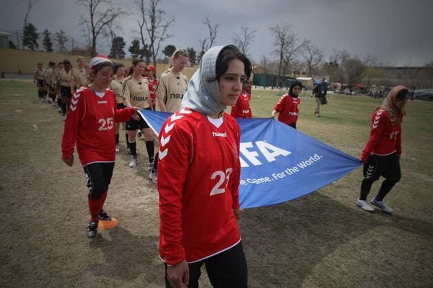 Players march into the pitch before a friendly match between Afghan women s national soccer team and NATO-led International Security Aid Force women s soccer team in Kabul, capital of Afghanistan, on April 1, 2011. The match ended with a 0-0 tie.  o0 Objekte Fahne FIFA Einmarsch
