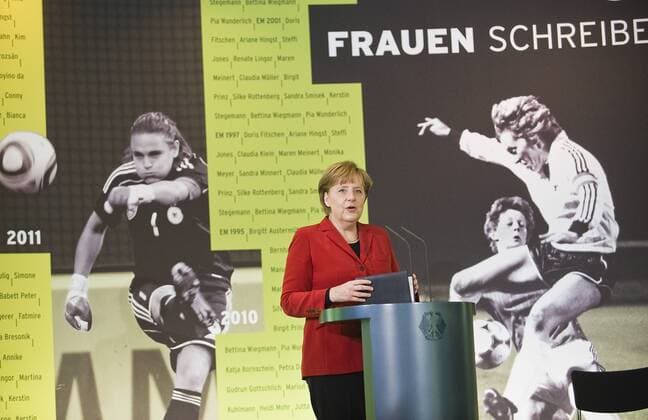 Bundeskanzlerin Angela MERKEL (CDU) bei der Eröffnungsrede vor Fotos von Nadine Angerer (li.) und Heidi Mohr, Halbfigur, Gestik, Geste --- Eröffnung der Ausstellung FRAUEN SCHREIBEN FUSSBALGESCHICHTE im Bundeskanzleramt Berlin o0 Schriftzug