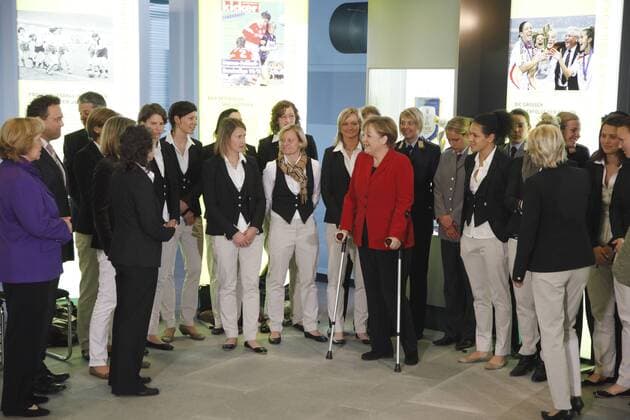 Eröffnung der Ausstellun FRAUEN SCHREIBEN FUSSBALLGESCHICHTE im Bundeskanzleramt Berlin --- Bundeskanzlerin Angela Merkel, CDU, rotes Jackett, inmitten der Spielerinnen der Fussballnationalmannschaft der Frauen o0 Totale Verletzung