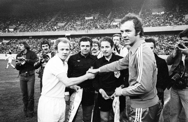 Begrüßung vor dem Landesmeister Finale 1975: Mannschaftskapitäne Billy Bremner (Leeds, li.) und Franz Beckenbauer (Bayern) beim Handschlag, dahinter Schiedsrichter Michel Kitabdjan (Frankreich) Wimpel Vereinswimpel tauschen Wimpeltausch Begrüßung begrüßen Handschlag Freude