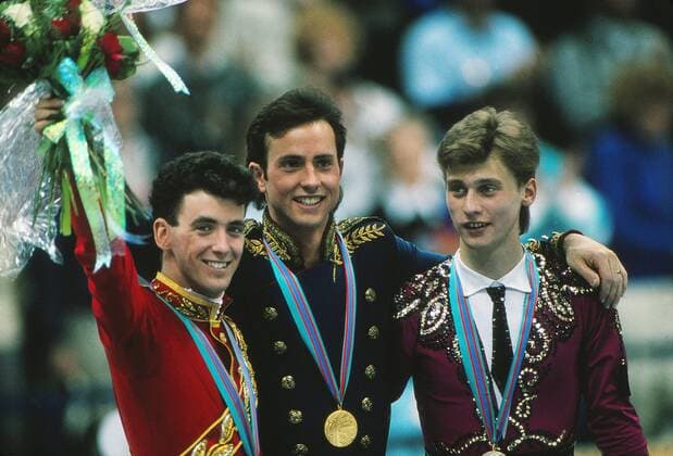 OLYMPIC LEGENDS: Brian Boitano Siegerehrung Eiskunstlauf in Calgary 1988, v.li. Brian Orser (Canada), Sieger Brian Boitano (USA) und Viktor Petrenko (Russia) Den Battle of the Brians zwischen Orser und Boitano entschied der Amerikaner für sich und löste damit beim kanadischen Heimpublikum große Enttäuschung aus.  o0 Olympiasieg Sieg Goldmedaille Siegerehrung Silbermedaille Bronzemedaille gold Silber Bronze Medal o0 Eiskunstlauf