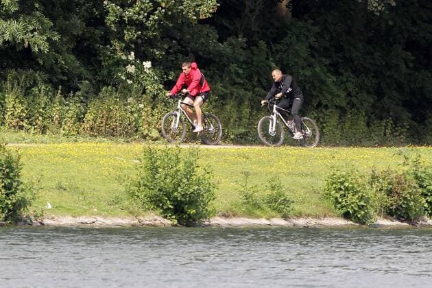 1.FC Köln Lukas Podolski hält sich fit für die Nationalmannschaft Runde mit dem Fahrrad um den Decksteiner Weiher Lukas Podolski mit Willi Breuer