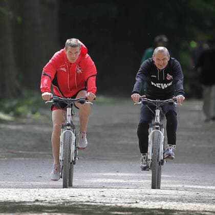 1.FC Köln Lukas Podolski hält sich fit für die Nationalmannschaft Runde mit dem Fahrrad um den Decksteiner Weiher Lukas Podolski mit Willi Breuer