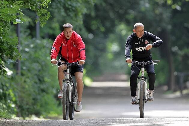1.FC Köln Lukas Podolski hält sich fit für die Nationalmannschaft Runde mit dem Fahrrad um den Decksteiner Weiher Lukas Podolski mit Willi Breuer