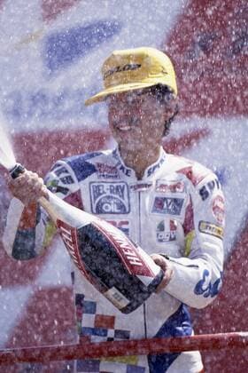 Dirk RAUDIES, Deutschland, Motorradfahrer, 125ccm-Klasse, jubelt bei der Siegerehrung, spritzt mit Sekt, Mai 1993. Einzelbild