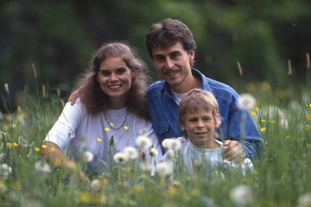Dirk RAUDIES, Deutschland, Motorradfahrer, 125ccm-Klasse, Porträt, Portrait, sitzt mit seiner Familie auf einer Blumenwiese, mit Ehefrau Birgit und Sohn Hannes, Brustbild, Porträt, Portrait, beim Grossen Preis von Deutschland auf dem Nürburgring, Juni 1993.