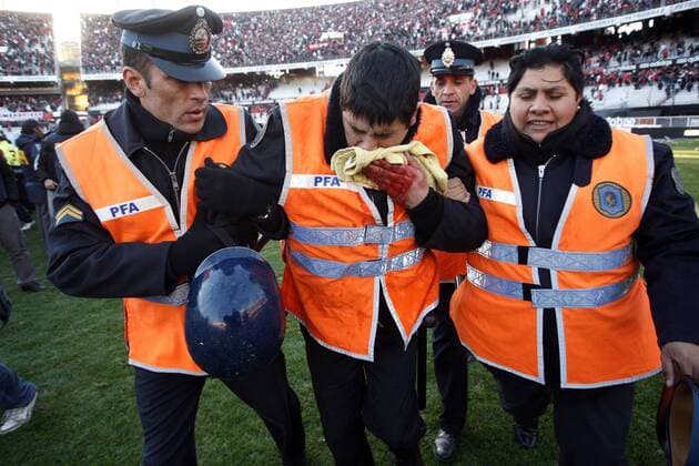 BUENOS AIRES, - A policeman (C) is injured by angry supporters of River Plate after their Argentina s first division second leg playoff soccer match in Buenos Aires, capital of Argentina, June 26, 2011. River Plate, the giant Argentine league club, suffered their biggest humiliation ever with relegation to the second division for the first time in the first leg of their play-off on Wednesday and tying 1-1 in the second leg match on Sunday. ---  o0 Polizei Polizist Sicherheit Stadionsicherheit Verletzung