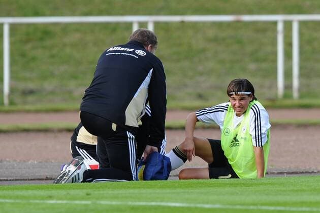 Fußball Training Deutsche Frauen- Nationalmannschaft am 02.07.2011 im Stadion am Eisenbrand in Meerbusch Ariane Hingst ( Deutschland ), rechts - wird verletzt am Spielfeldrand behandelt