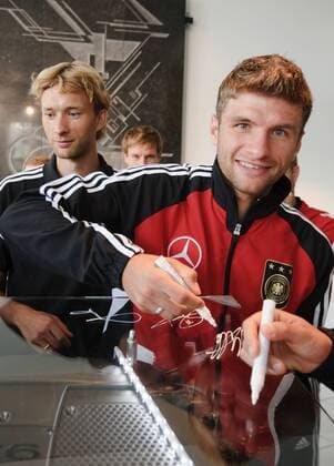 Die Spieler der Nationalmannschaft unterschreiben auf einem Motor. Thomas MÜLLER und Simon ROLFES l. Werksführung der deutschen Fussball Nationalmannschaft im Motorenwerk von Mercedes-Benz in Bad Cannstatt Stuttgart am 9.8.2011.