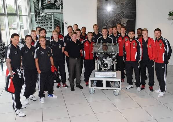 Die Nationalmannschaft bei einem Teamfoto, Mannschaftsbild im Werk, mit einem Ausstellungs-Motor. Dabei: Werksleiter Günter KASPER. Fussball: Werksfuehrung der deutschen Fussball- Nationalmannschaft der Maenner am 09.08.2011 im Motorenwerk Bad Cannstatt, Stuttgart, 09.08.2011  o00 Wirtschaft