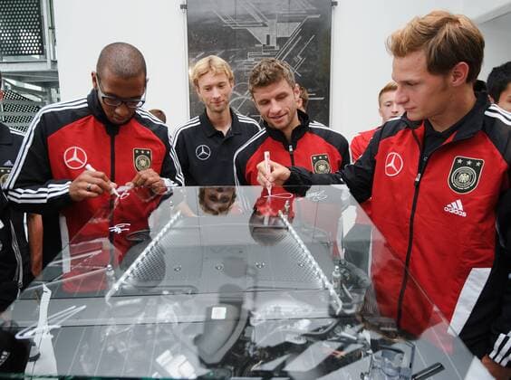 Die Spieler der Nationalmannschaft unterschreiben auf einem Motor. Jerome BOATENG (Deutschland), Simon ROLFES (Deutschland), Thomas MÜLLER (Deutschland), Benedikt HÖWEDES (DFB Deutschland). (von links). Fussball: Werksfuehrung der deutschen Fussball- Nationalmannschaft der Maenner am 09.08.2011 im Motorenwerk Bad Cannstatt, Stuttgart, 09.08.2011 