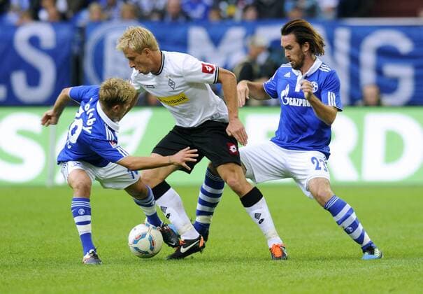 Fussball-Bundesliga, Deutschland, Herren, Saison 2011 2012, 4. Spieltag, Veltins Arena Gelsenkirchen: FC Schalke 04 (blau) - Bor. Mönchengladbach (weiss) 1:0; v.li.: Lewis Holtby (S04), Mike Hanke (Gladbach), Christian Fuchs (S04). Aktion, Einzelbild.