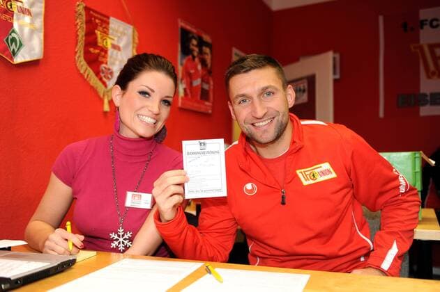 Fussball, Herren, Saison 2011 2012, 2. Bundesliga, 1. FC Union Berlin, Mannschaftskapitän Torsten Mattuschka zeichnete als erster Spieler die Alte-Försterei-Aktie in der Geschäftsstelle, Mattuschka mit Zeichnungsbestätigung, links Lisa Fedde, 06.12. 2011,