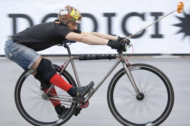 15.01.12 London, England. Player stretching on his bike ahead of the London International Invitational bike polo quarter finals match at The Bike Show between Dead Rappers (black shirts) from London and El Club (yellow bibs) from Barcelona, Spain at ExCeL Centre, East London. xDavidxFearn ActionxPlusx  ActionPlus11235031