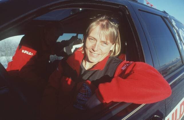 Jutta Kleinschmidt (Motorsportlerin) 02 00 mapo Frau Motorsport Auto Autosport Rallyes Rallye Rallyesport Rallyefahrerin Rallyefahrer Fahrerin Fahrer blond leger sportlich Jacke Anorak rot-schwarz Logo Fulda - Challenge sitzend Auto PKW Wagen am Steuer Lenkrad halb quer lächelnd aus der Tür Autotür aus dem Fenster Autofenster schauend durch das Fenster Sonnenbrille ins Haar geschoben