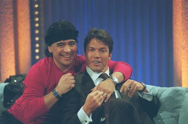 Lothar Matthäus (re.) und Diego Maradona in Wetten, dass...? (ZDF) 01 01 her Mann ehemaliger Fußballspieler Sportler Profi-Sport Profisport Fußball Ex-Fußballer Fußballprofi dunkelhaarig sitzend Saal Studio Kulisse Dekoration Bank Sitzbank Sofa Couch halb quer herumalbernd angelehnt umarmend Wetten, dass...? (ZDF) am 20.01.2001 in Bremen Farbnegativ