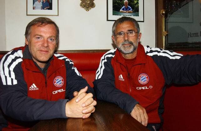 Hermann Gerland (li.) und Gerd Müller 01 02 wow Mann Fußball Fußballtrainer Trainer Co-Trainer Regionalliga-Mannschaft des FC Bayern München dunkelhaarig leger sportlich Sportjacke Trainingsjacke Adidas Werbung für Opel sitzend Tisch halb quer lächelnd posierend