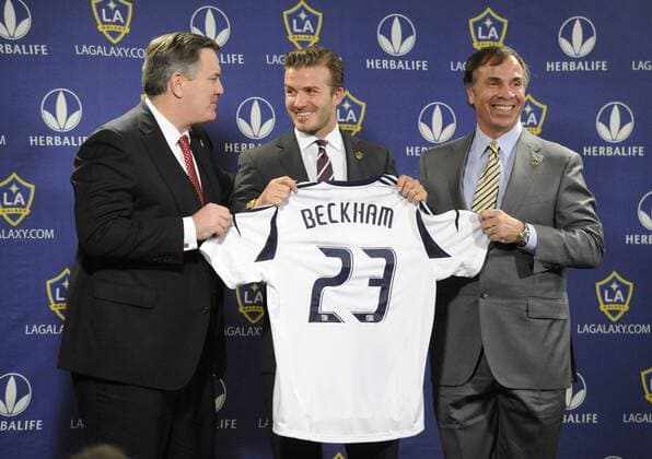 David Beckham (C) with AEG president and CEO Tim Leiweke (L) and General Manager and Head Coach, Bruce Arena (R) poses with a new jersey after announcing a two-year contract with the Los Angeles Galaxy during a news conference at the Staples Center in Los Angeles on January 19, 2012.  LAP20120119113