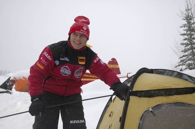 Jutta Kleinschmidt bei der Fulda Challenge 2005 in Kanada 02 05 mapo Frau Sportlerin Motorsport Motorsportlerin Autosport Auto Rallye Rallyesport Rallyefahrerin sportlich Sportkleidung Mütze halb quer stehend draußen lächelnd zur Seite schauend am Zelt