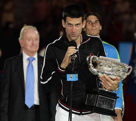 Australian Open 2012, Melbourne Park,ITF Grand Slam Tennis Tournament, Männer Finale,Siegerehrung, Präsentation, Novak Djokovic (SRB) mit Pokal hält Rede,Ansprache,im Hintergrund links Tennis Legende Rod Laver (AUS) und rechts Finalist Rafael Nadal (ESP),Halbkörper,Querformat