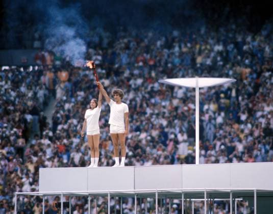 Eröffnungsfeier der Olympischen Spiele 1976 in Montreal: Stephane Prefontaine und Sandra Henderson (beide Kanada) entzünden als letzte Fackelläufer das Olympische Feuer
