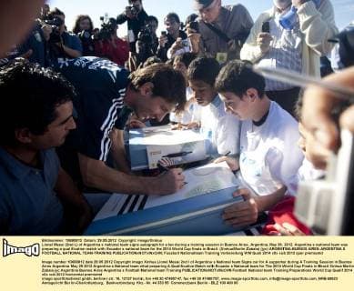 Lionel Messi (2nd L) of Argentina s national team signs autograph for a fan during a training session in Buenos Aires, Argentina, May 29, 2012. Argentina s national team was preparing a qualification match with Ecuador s national team for the 2014 World Cup finals in Brazil. (Xinhua Martin Zabala) (jyc) ARGENTINA-BUENOS AIRES-ARGENTINA S FOOTBALL NATIONAL TEAM-TRAINING 