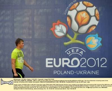 ITAR-TASS: DONETSK, UKRAINE. JUNE 13, 2012. A man walks past a promotional billboard showing the UEFA Euro 2012 logo. The city of Donetsk is hosting some of the matches of the Euro 2012 football tournament.  RE100F4D
