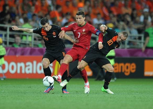 Football - European Championships 2012 - Portugal vs. Netherlands Christiano Ronaldo of Portugal glides past the tackles of Robin Van Persie and Wesley Sneijder of the Netherlands at the Metalist Stadium, Kharkiv, Ukraine 