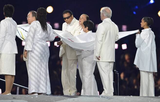 back (L-R) Ban Ki Moon, Muhammad Ali (C) with wife Lonnie, Shami Chakrabarti, Marina Silva - front: Sally Becker, Leymah Gbowee, Daniel Barenboim carrying the Olympic flag during the opening ceremony of the London 2012 Summer Olympics, July 27, 2012, in Stratford, London. The ceremony, welcoming more than 10,000 athletes from 204 nations, were a celebration of the hundreds of years of British history and culture.  OLY20120727501