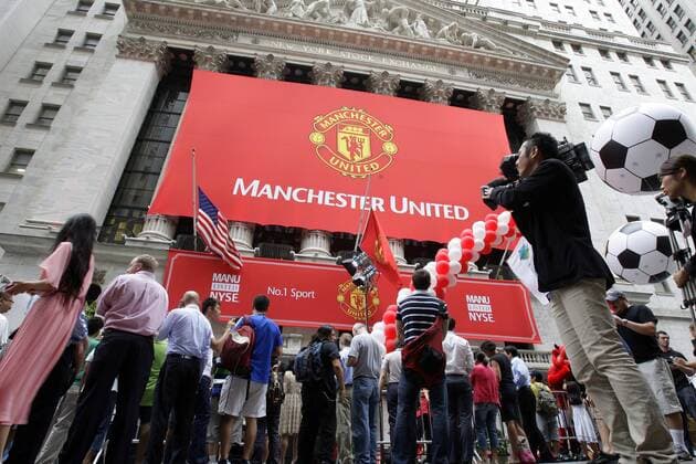 Members of the media and stand out side of the New York Stock Exchange on the morning that Manchester United Lists its Initial Public Offering at the NYSE on Wall Street In New York City on August 10, 2012. Manchester United will begin trading today on the NYSE under the ticker symbol MANU.  NYP20120810101