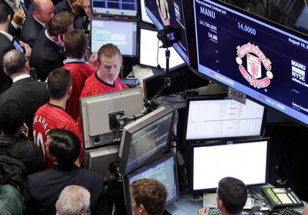 Traders wear the Manchester United Jersey at the New York Stock Exchange on the day when Manchester United Lists its Initial Public Offering at the NYSE on Wall Street In New York City on August 10, 2012. Manchester United will begin trading today on the NYSE under the ticker symbol MANU.  NYP20120810116