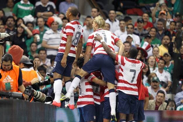 15 August 2012: Michael Orozco Fiscal (USA) (4) is mobbed by teammates after scoring a goal. Terrence Boyd (USA) (18), Brek Shea (USA) (11), and Maurice Edu (USA) (7) climb the boards in front of a section of U.S. fans. The United States Men s National Team defeated the Mexico Men s National Team 1-0 at Estadio Azteca in Mexico City, Mexico in an international friendly soccer match. SOCCER: AUG 15 Mexico v USA Icon918120815001 EDITORIAL USE ONLY