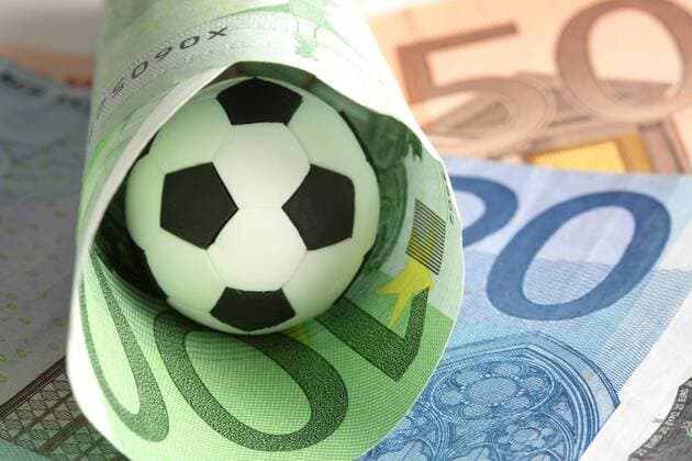 Wettskandal - Fußball liegt ein einem eingerollten 100 Euro Geldschein