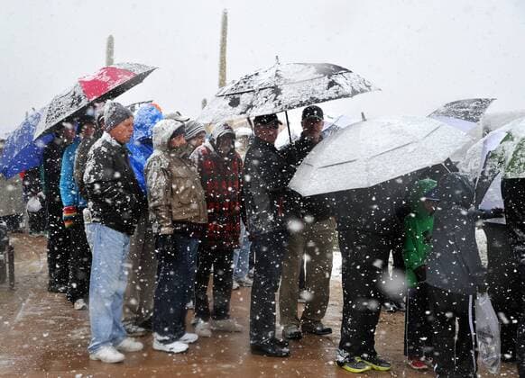 Fans wait in line in the snow for buses to take them to their cars after snow suspended the first round of the Accenture World Golf Championship at The Golf Club at Dove Mountain in Marana, Arizona February 20, 2013.  PXP2013022010