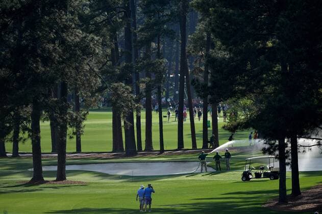 Maintenance workers water the green during a practice round at the Master golf tournament at Augusta National Golf Club on April 8, 2013 in Augusta, Georgia.  AUG20130408340