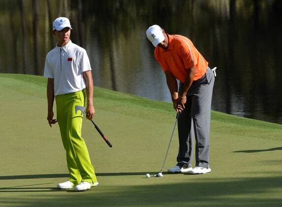 Tiger Woods (R) and Guan Tianlang (L), of China, line up putts on the 16th hole during a practice round before the Master golf tournament at Augusta National Golf Club on April 8, 2013 in Augusta, Georgia.  AUG20130408343