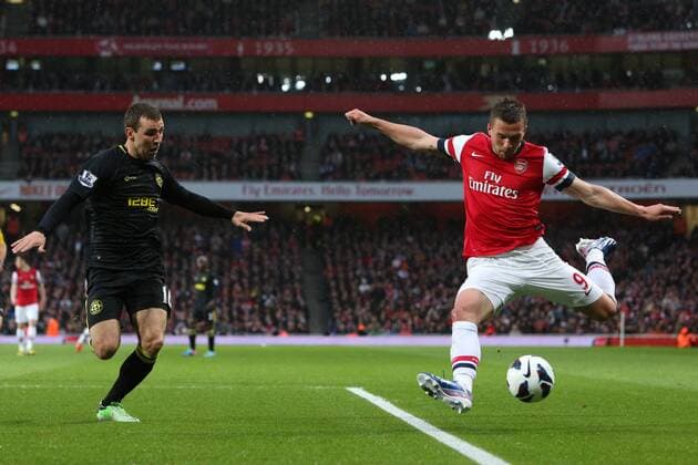 Football - 2012 2013 Premier League - Arsenal vs Wigan Lukas Podolski of Arsenal crosses while under pressure from Wigan s James McArthur at the Emirates Stadium, London 